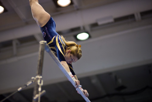 Junior Taylor Redmond spots the floor as she transitions from the lower to the upper bar. 