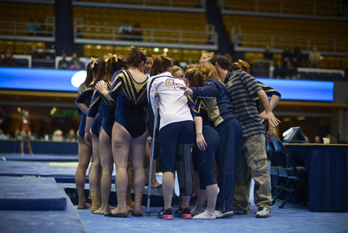 Members of the gymnastics team huddles together as they move on to the floor exercise. 