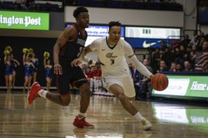 Freshman guard Jair Bolden dribbles around a Dukes defender. The game marked the first career start for Bolden who finished with five points, four assists and four rebounds. Ethan Stoler | Hatchet Photographer