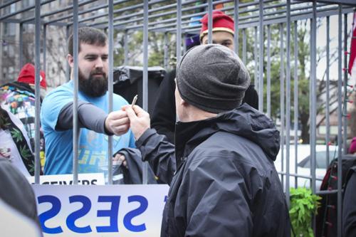 A volunteer inside a cage hands out a marijuana joint. DCMJ gave out more than 8,000 free joints Friday. Julia Abriola | Hatchet Photographer